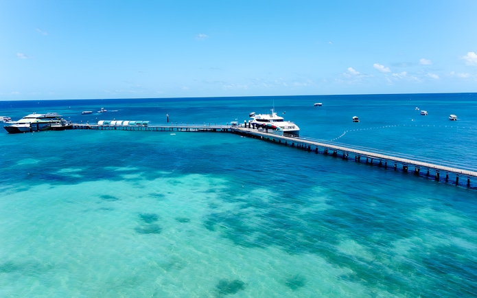 Docked boat at Green Island pier, Cairns, with clear turquoise waters and distant boats.