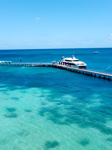 Docked boat at Green Island pier, Cairns, with clear turquoise waters and distant boats.