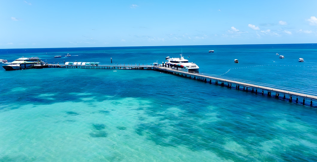 Docked boat at Green Island pier, Cairns, with clear turquoise waters and distant boats.