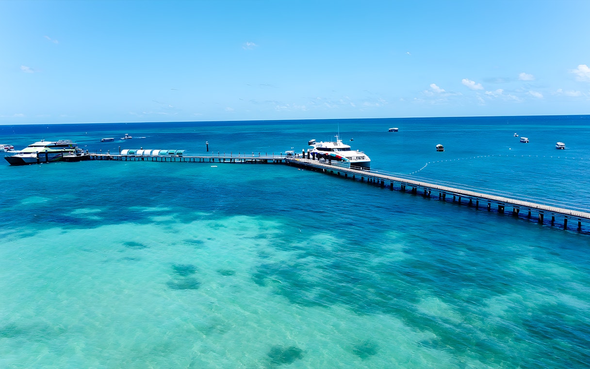 Docked boat at Green Island pier, Cairns, with clear turquoise waters and distant boats.