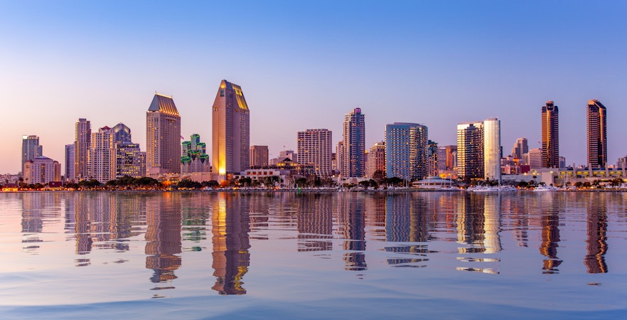 San Diego skyline with buildings silhouetted against a vibrant sunset sky.
