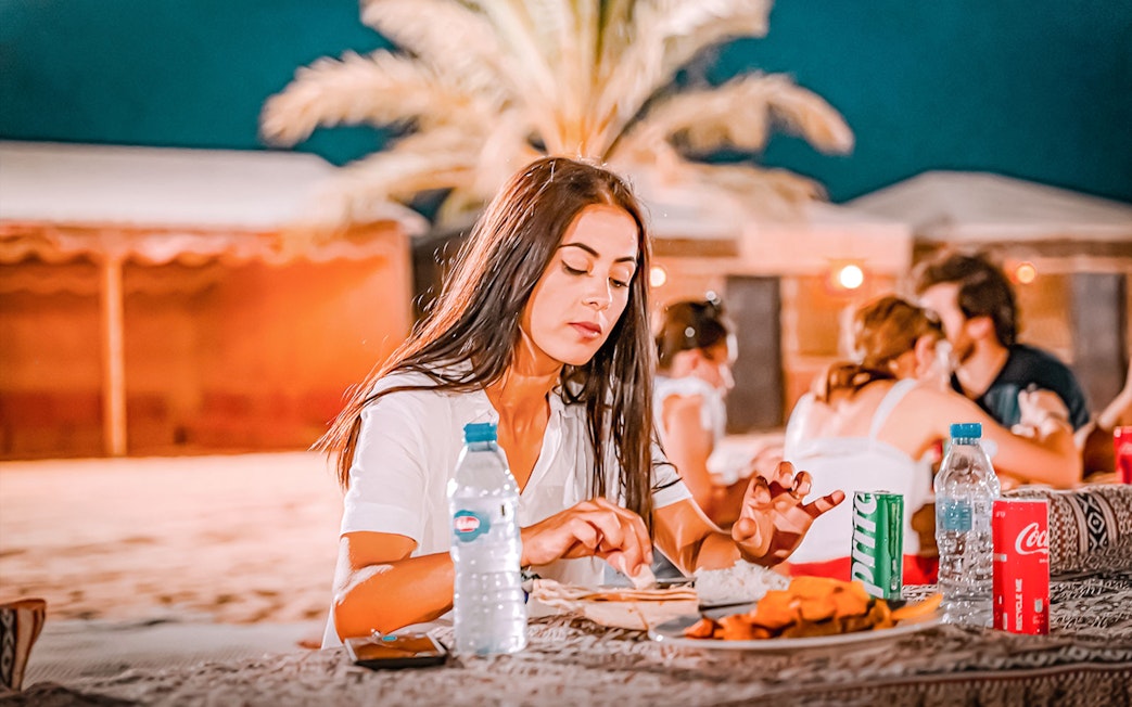 Dinner at Abu Dhabi Desert safari with guests enjoying traditional cuisine.