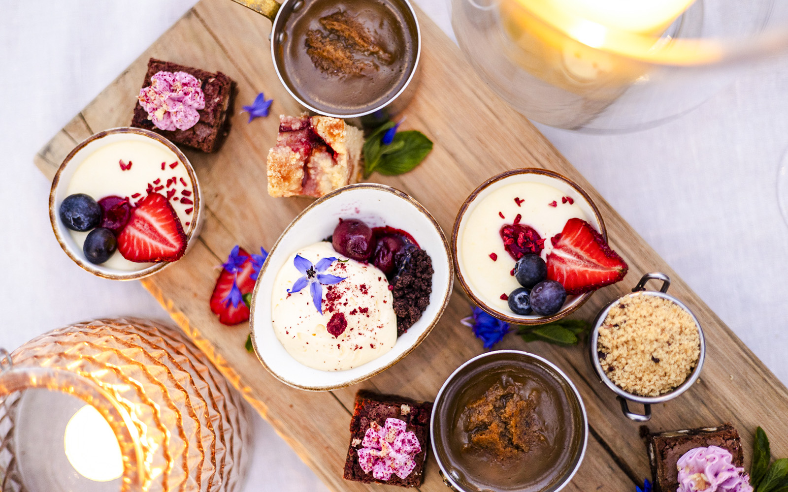 Assorted desserts with berries and cream on a wooden board, part of the "Desserts on board" experience.