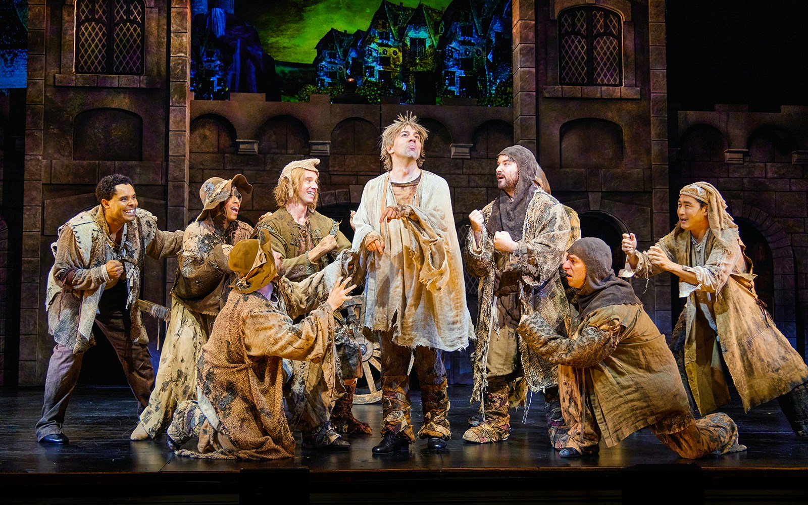 Actors in medieval costumes performing a scene from Spamalot on stage.