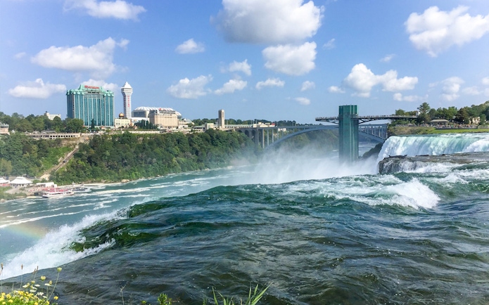 Aerial view of Niagara Falls with surrounding buildings and Rainbow Bridge.