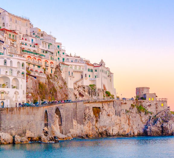 Cliffside buildings overlooking the sea at sunset in Amalfi, Italy.