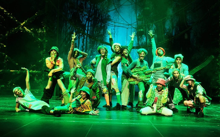 Performers in colorful costumes on stage during "Peter, El Musical" show.