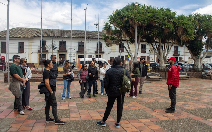 Tourists receiving a briefing from a guide in a historic town square.