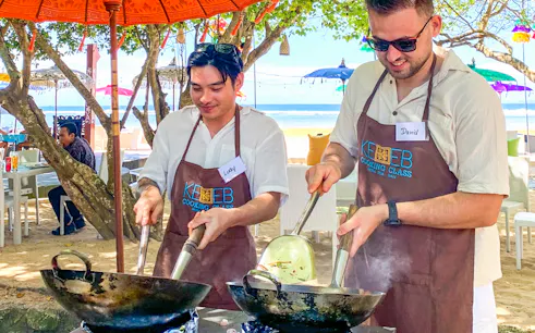 Participants cooking at Kekeb Balinese Cooking Class, Nusa Dua beach setting.