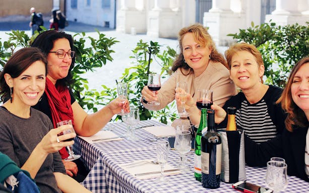 Friends enjoying wine at an outdoor cafe in Rome.
