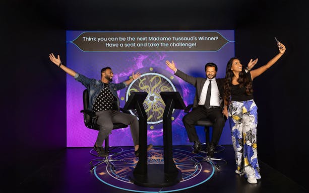 Visitors posing with Anil Kapoor wax figure at KBC set, Madame Tussauds Dubai.