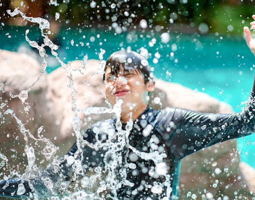Kid enjoying water splash at amusement park pool.