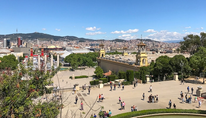 Cable car ascending Parc de Montjuic, Barcelona, with cityscape and Mediterranean Sea in the background.