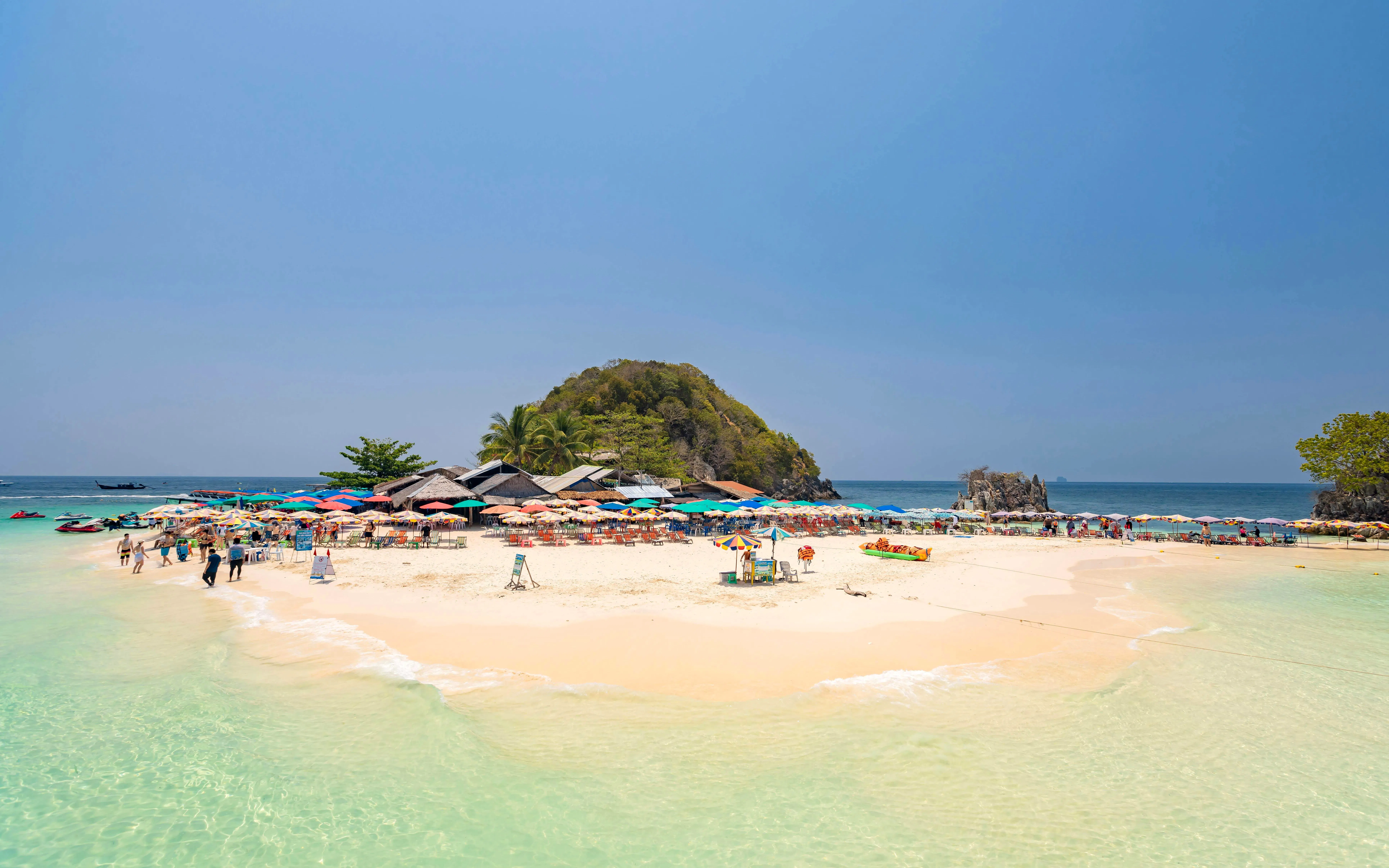 Phuket tour: tourists on Khai Island beach with colorful umbrellas and clear water.