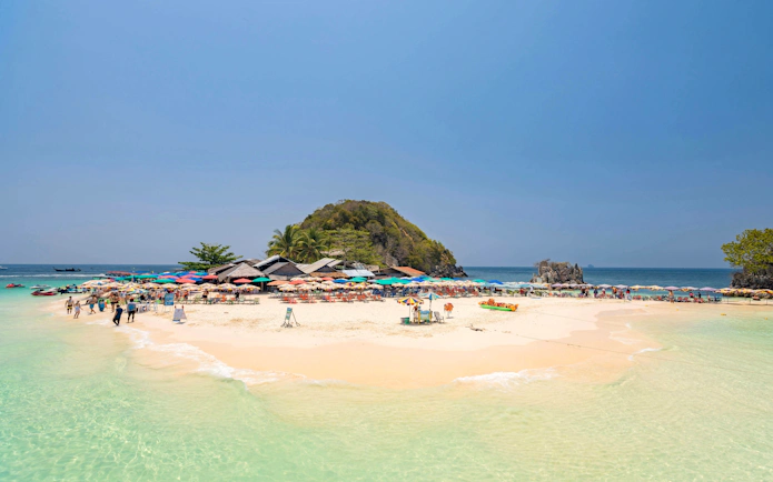 Phuket tour: tourists on Khai Island beach with colorful umbrellas and clear water.