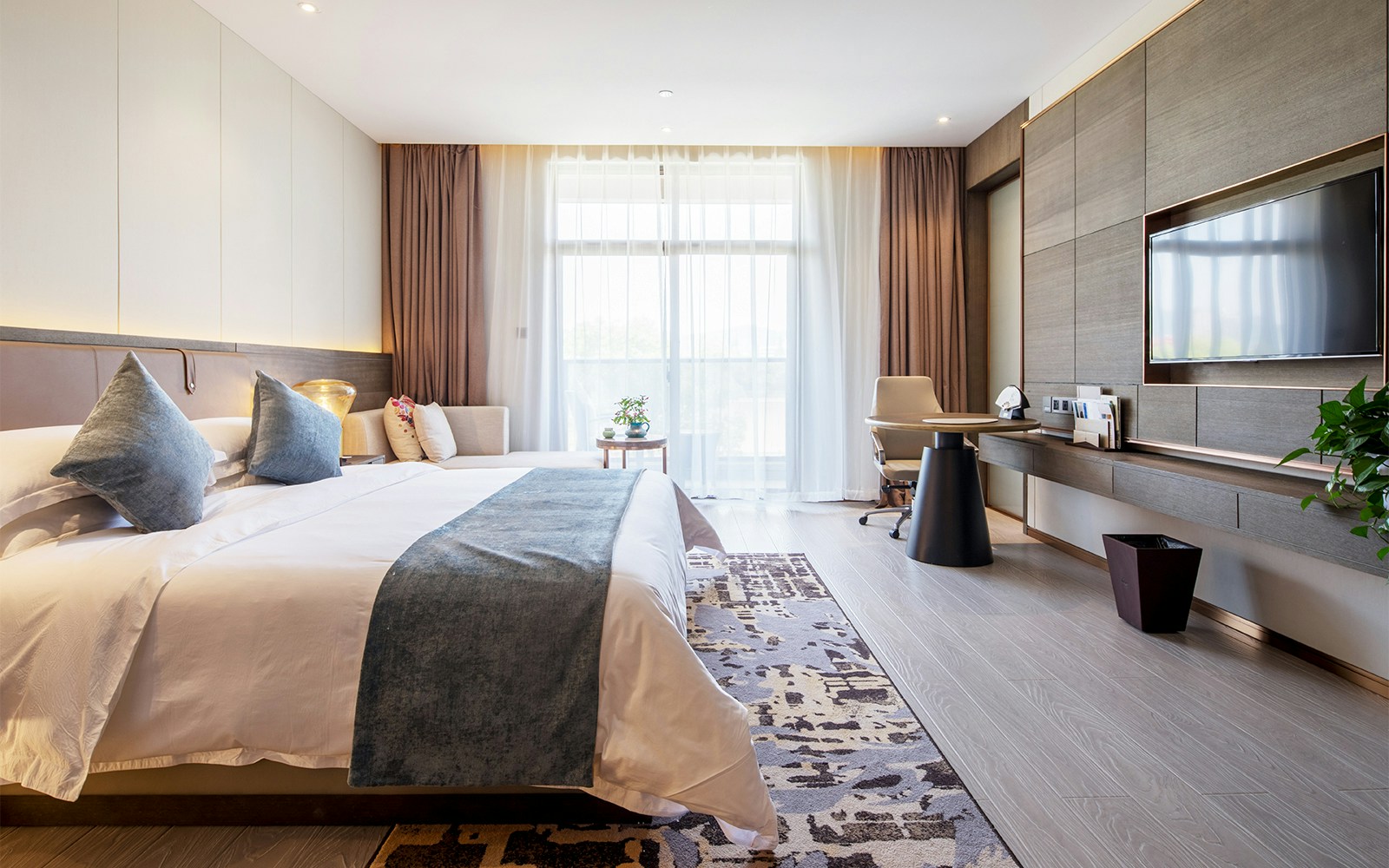 Luxury hotel room with king-size bed, modern decor, and large window.