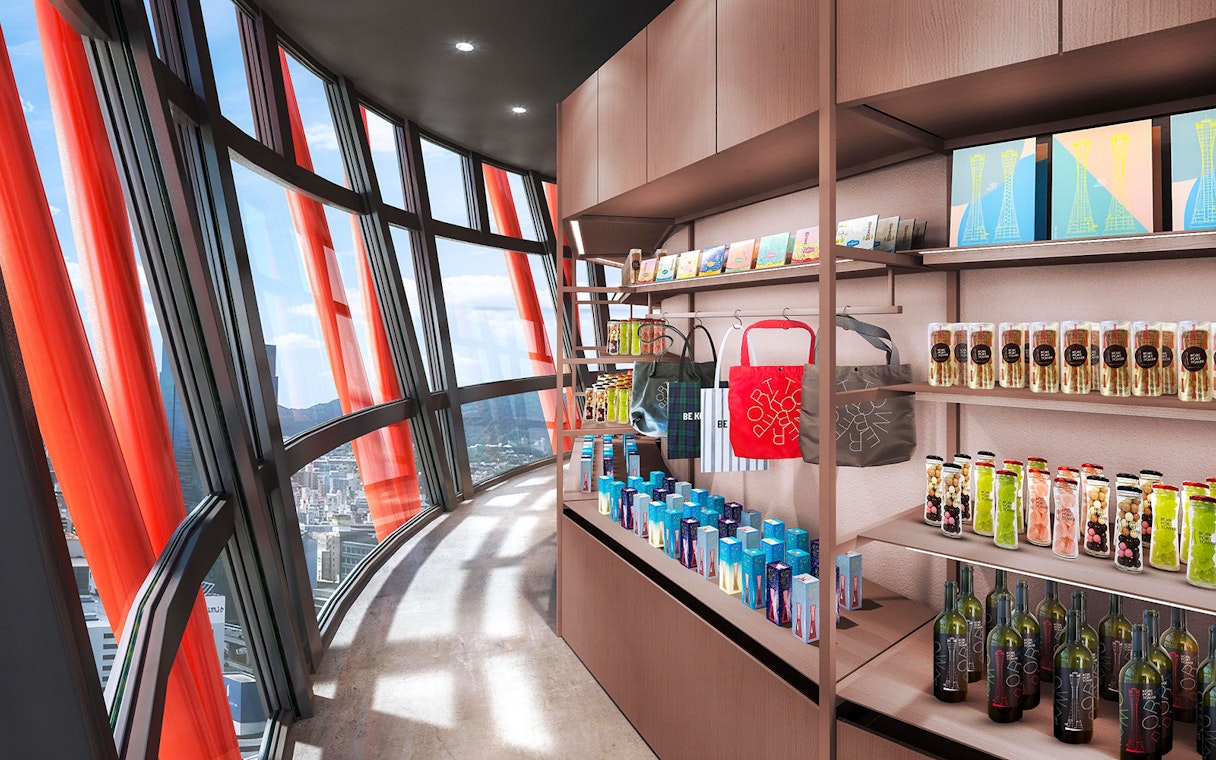 Gift shop inside Kobe Port Tower with city view through curved windows.