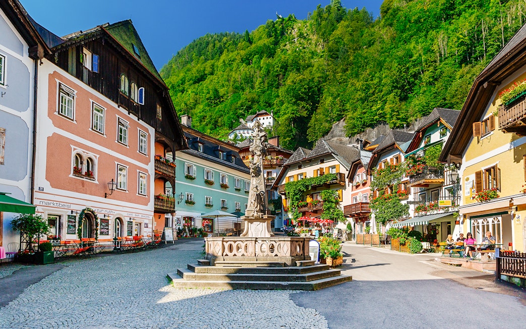 Colorful buildings and central fountain in Hallstatt village square, Austria.