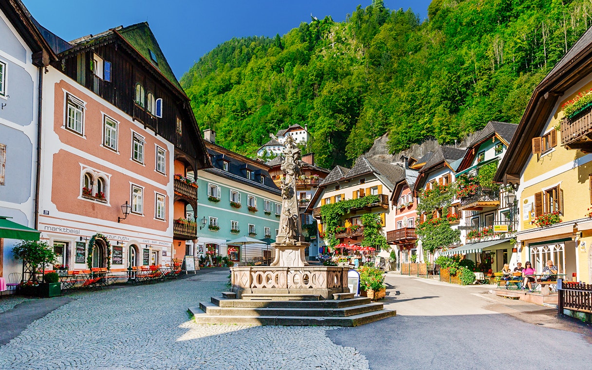 Colorful buildings and central fountain in Hallstatt village square, Austria.