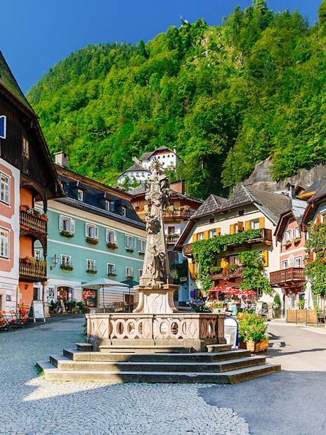 Colorful buildings and central fountain in Hallstatt village square, Austria.