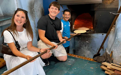 Couple learning to bake Amazigh bread in a traditional oven.