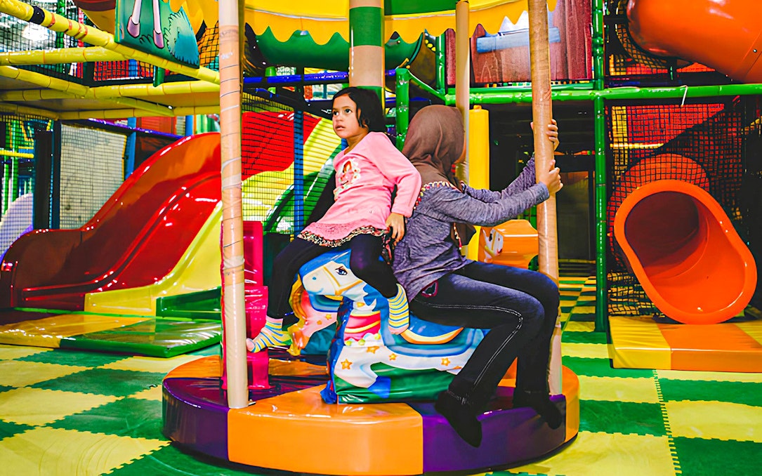 Children playing on a carousel at Jungle Gym, KL East Mall, Malaysia.