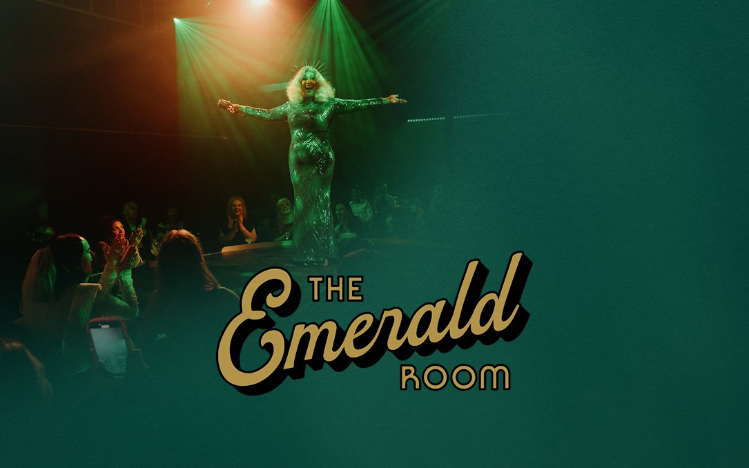 Performer on stage at The Emerald Room with audience applauding.
