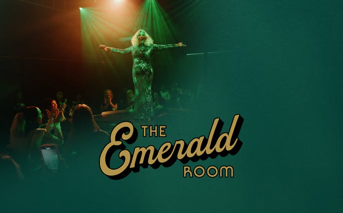 Performer on stage at The Emerald Room with audience applauding.