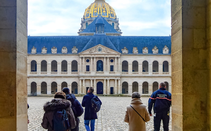 Visitors walking in the courtyard of Les Invalides, Paris, with the dome in view.