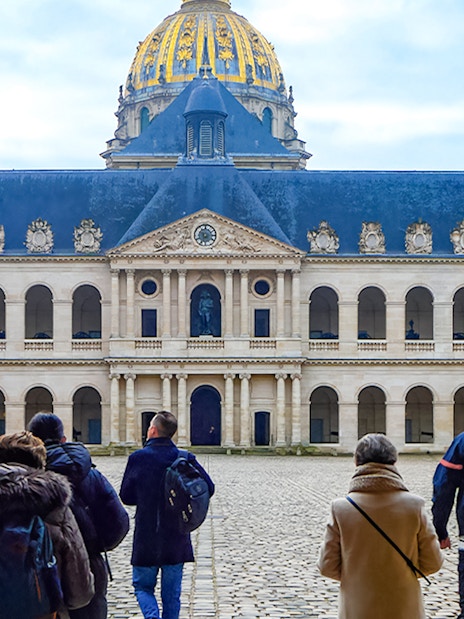 Visitors walking in the courtyard of Les Invalides, Paris, with the dome in view.