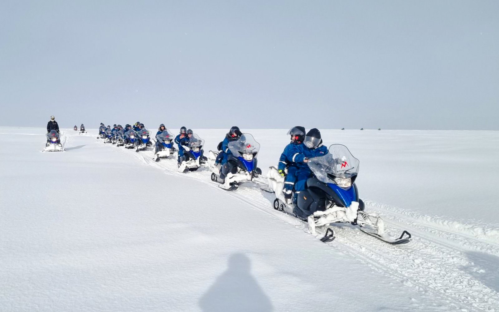 Snowmobile group tour from Gullfoss waterfall across snowy landscape.