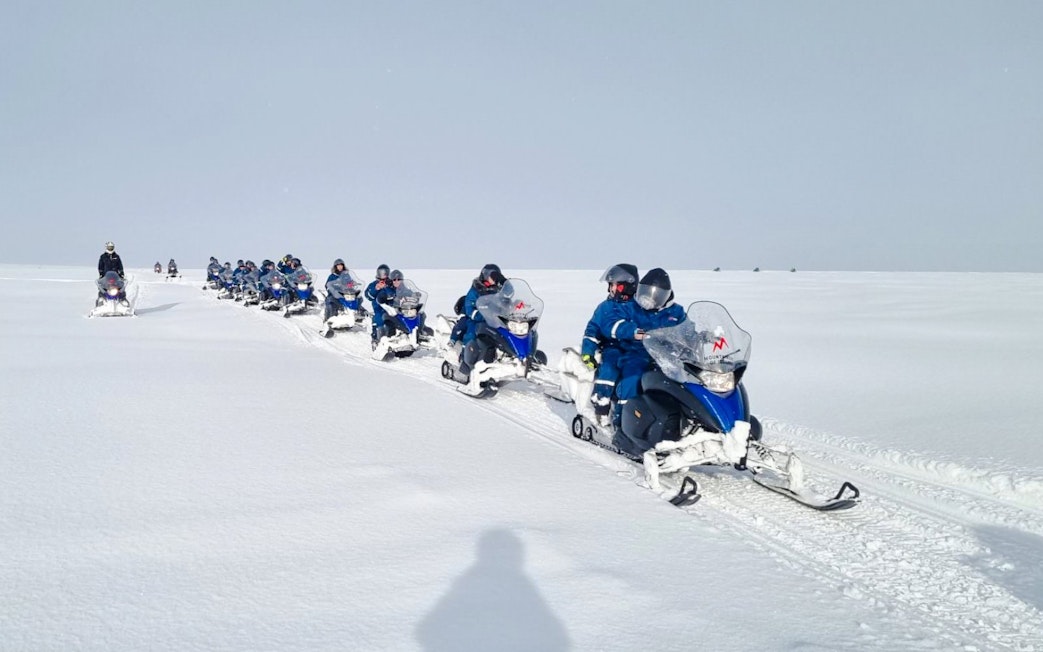 Snowmobile group tour from Gullfoss waterfall across snowy landscape.