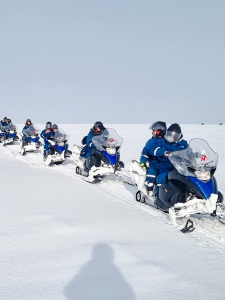 Snowmobile group tour from Gullfoss waterfall across snowy landscape.