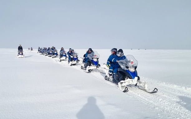 Snowmobile group tour from Gullfoss waterfall across snowy landscape.
