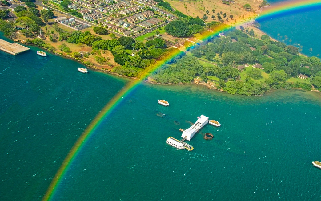 Aerial view of Arizona Memorial at Pearl Harbor with a rainbow over the water.