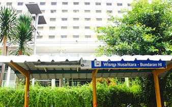 Wisma Nusantara MRT station sign in Jakarta, surrounded by greenery.