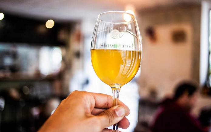 Hand holding a glass of cider during a food tour in La Barceloneta.