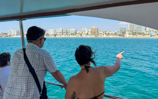 Tourists on a boat enjoying a view of Larnaca's coastline during a bay cruise.