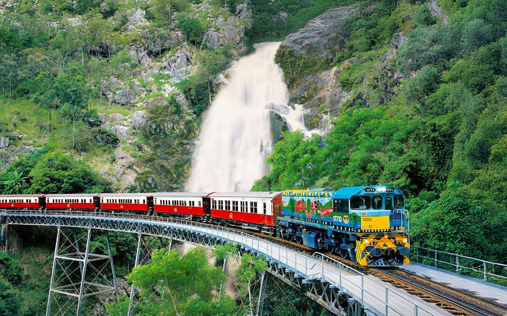 Kuranda Scenic Railway train crossing bridge with waterfall in background, Queensland, Australia.