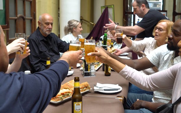 Group toasting with drinks at a table during Valletta food tour.