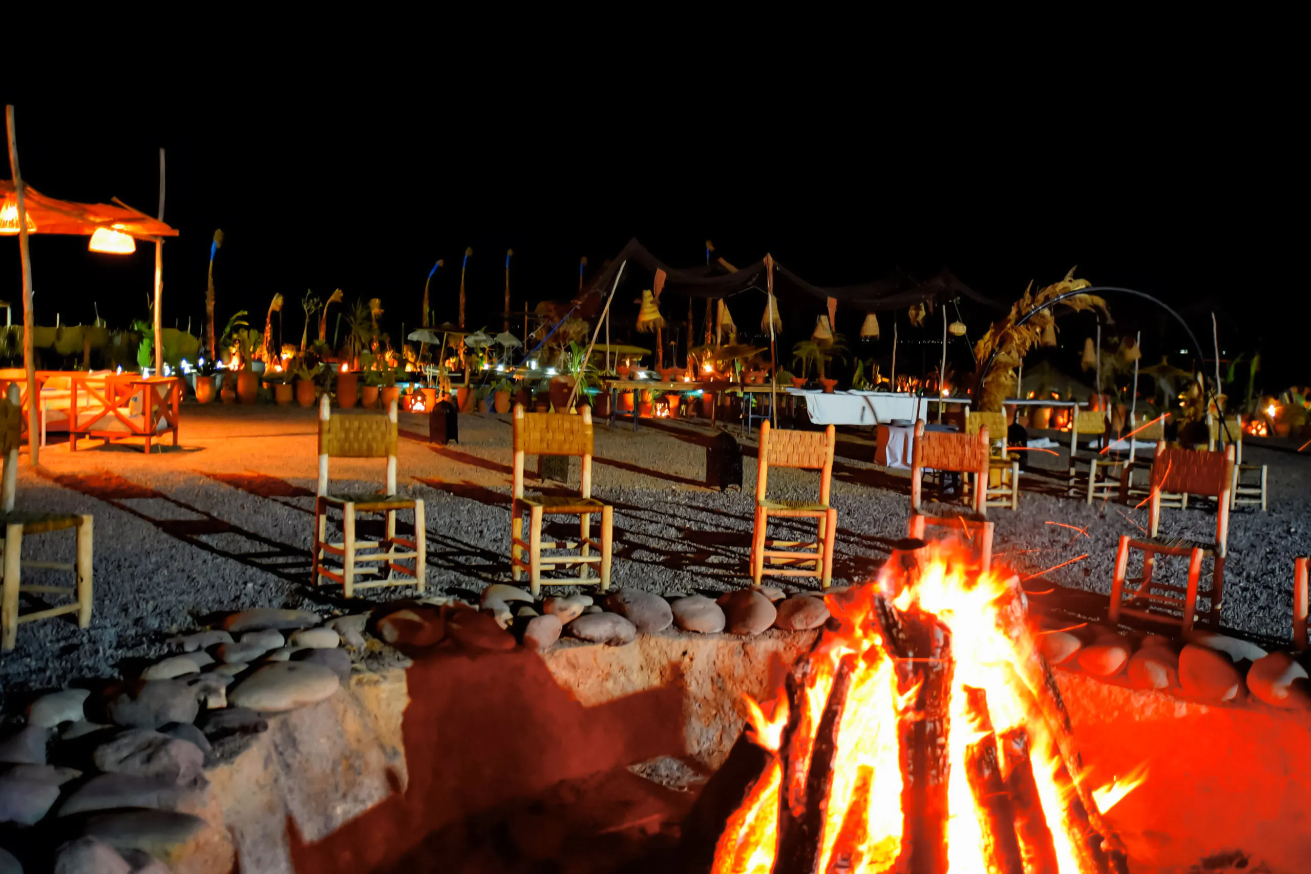 Nighttime desert campfire setting with chairs in Marrakech.