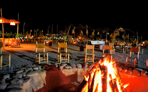 Nighttime desert campfire setting with chairs in Marrakech.