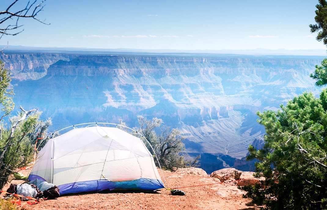 Tent on cliff edge at Point Sublime, North Rim Grand Canyon, overlooking vast canyon landscape.