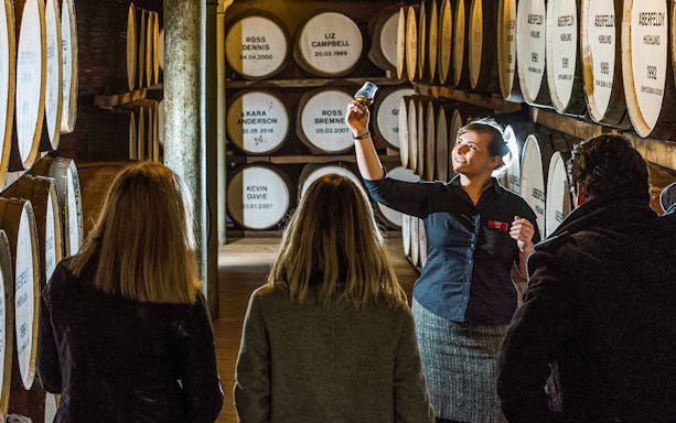 Tour guide showing whisky barrel room during Edinburgh whisky experience.