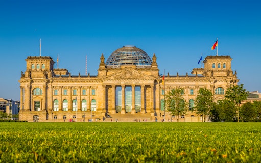 Reichstag building in Berlin, Germany, with glass dome and flags, part of Parliament District tour.