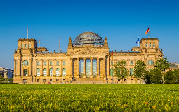 Reichstag building in Berlin, Germany, with glass dome and flags, part of Parliament District tour.