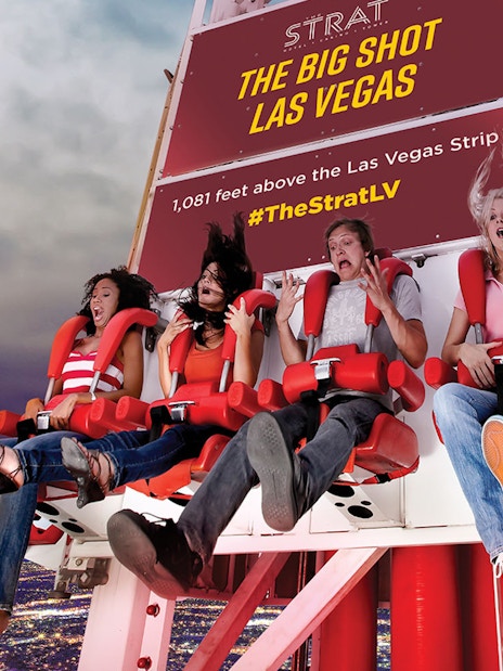 Riders on the Big Shot thrill ride at The Strat, Las Vegas, with city lights below.