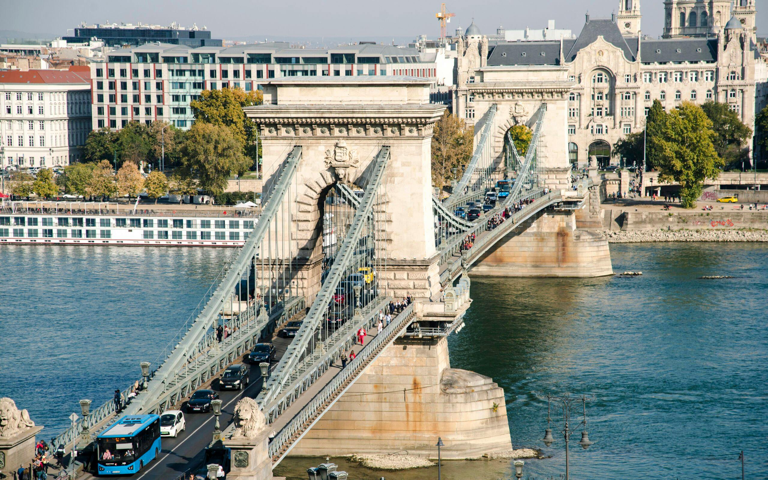 Széchenyi Chain Bridge spanning the Danube River in Budapest, Hungary, with traffic and pedestrians.