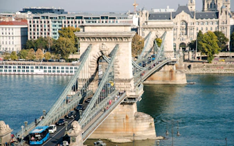 Széchenyi Chain Bridge spanning the Danube River in Budapest, Hungary, with traffic and pedestrians.