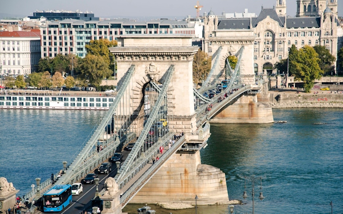 Széchenyi Chain Bridge spanning the Danube River in Budapest, Hungary, with traffic and pedestrians.
